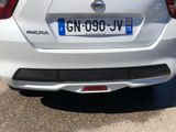 the rear end of a white car parked in a parking lot