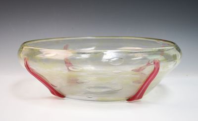 un saladier en verre avec une poignée rouge posé sur une table blanche