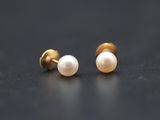 a pair of pearl earrings on a black surface