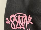 a black beanie with a pink logo on it