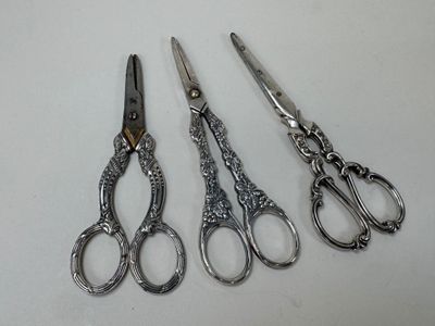 three pairs of silver scissors sitting next to each other on a table