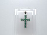 une petite croix verte exposée dans une vitrine transparente