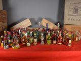 many bottles of alcohol sitting on a table with a red table cloth