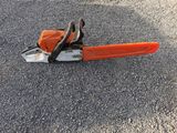 an orange chainsaw sitting on the ground in the middle of a parking lot