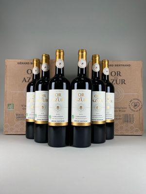 six bottles of red wine sit in front of a cardboard box