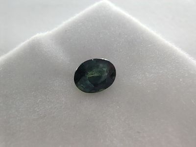 un gros plan d'un saphir vert posé sur un tissu blanc