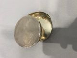 un petit récipient en argent posé sur une table, avec l'ombre d'une personne