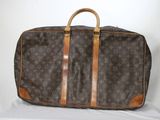 un sac Louis Vuitton marron et beige posé sur une surface blanche