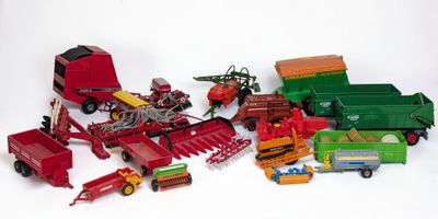 de nombreux jouets représentant des machines agricoles, disposés sur une surface blanche