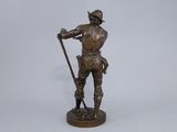 bronze statue of a man with a cane and hat on a white background
