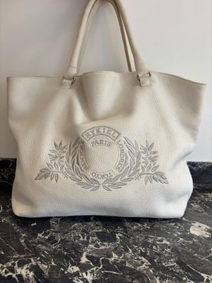 un sac fourre-tout en cuir blanc orné d'un blason sur le devant