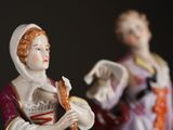 two figurines of a woman and a man standing next to each other