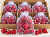 six décorations de Noël rouges dans une boîte, sur fond blanc