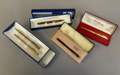 trois stylos et un stylo dans une boîte posée sur une table