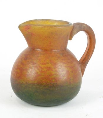 un vase marron et vert muni d'une anse, sur un fond blanc
