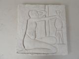 un relief blanc représentant un homme assis sur une table