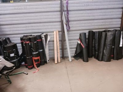de nombreux rouleaux de bâches noires dans un garage