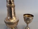 un vase en argent et une coupe en argent posés sur une table