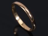 a close up of a gold wedding ring on a black surface