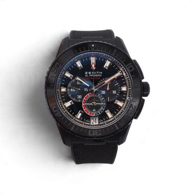 La montre est noire, avec une trotteuse rouge et une trotteuse bleue.