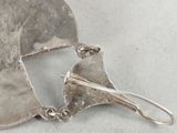 a close up of a silver plate with a pair of earrings on it