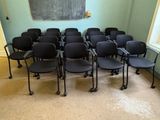 rows of black chairs in a room with a chalkboard on the wall