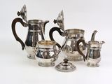 three pieces of silver tea and coffee set on a white surface