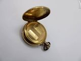a small gold pocket watch on a white surface