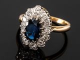 a close up of a blue sapphire and diamond ring on a black surface