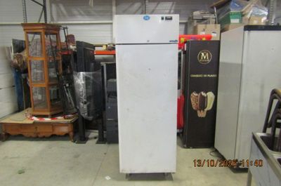 a refrigerator in a warehouse with other appliances in the background