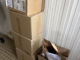 a stack of boxes sitting on the floor next to a trash can