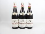 trois bouteilles de vin posées les unes à côté des autres sur une surface blanche
