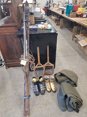 Plusieurs paires de chaussures et une paire de skis sont posées par terre