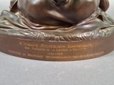 a bronze statue of a man laying on a pillow