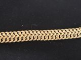 gros plan d'un bracelet en or sur une surface noire