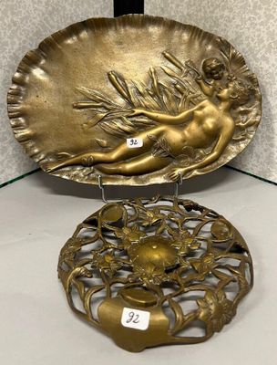 un plateau en or orné d'une dame et d'une fleur, posé sur une étagère en verre
