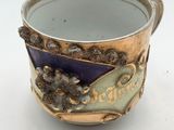 a purple and gold cup sitting on a white surface