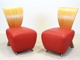 pair of red leather chairs with wooden legs in a white room