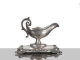 un plat ancien en argent orné d'un oiseau, posé sur un socle