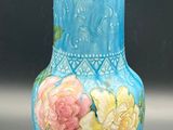 a blue vase with yellow and pink flowers on it