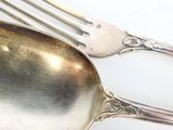 une cuillère et une fourchette en argent posées sur une table blanche