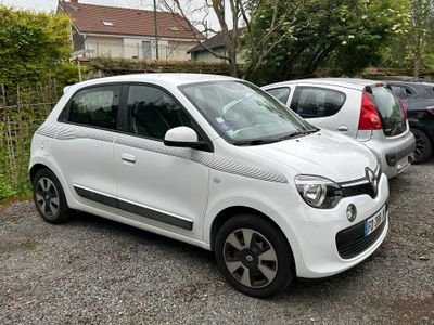 a small white car parked in a lot next to other cars
