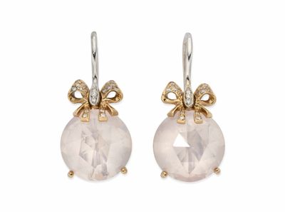 une paire de boucles d'oreilles ornées d'une pierre blanche et d'un nœud doré