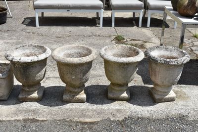 four stone vases sitting on a concrete slab