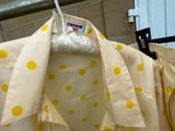 une chemise à pois jaunes suspendue à un portant