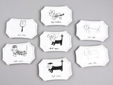 six assiettes blanches ornées de dessins d'animaux sur un fond gris