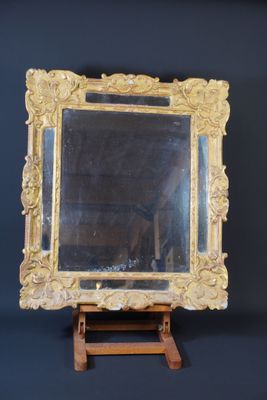 a mirror on a small wooden stand against a black wall
