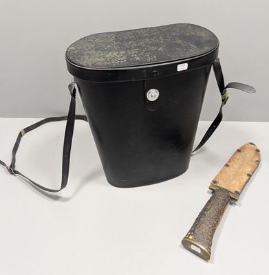 un seau noir contenant un couteau et un porte-couteau, posé sur une table