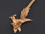 an image of a gold bird broochle with a diamond in its beak
