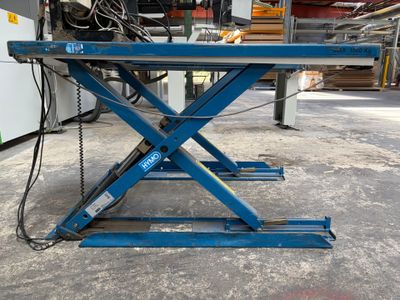 une paire de ciseaux bleus posée sur une table dans un entrepôt